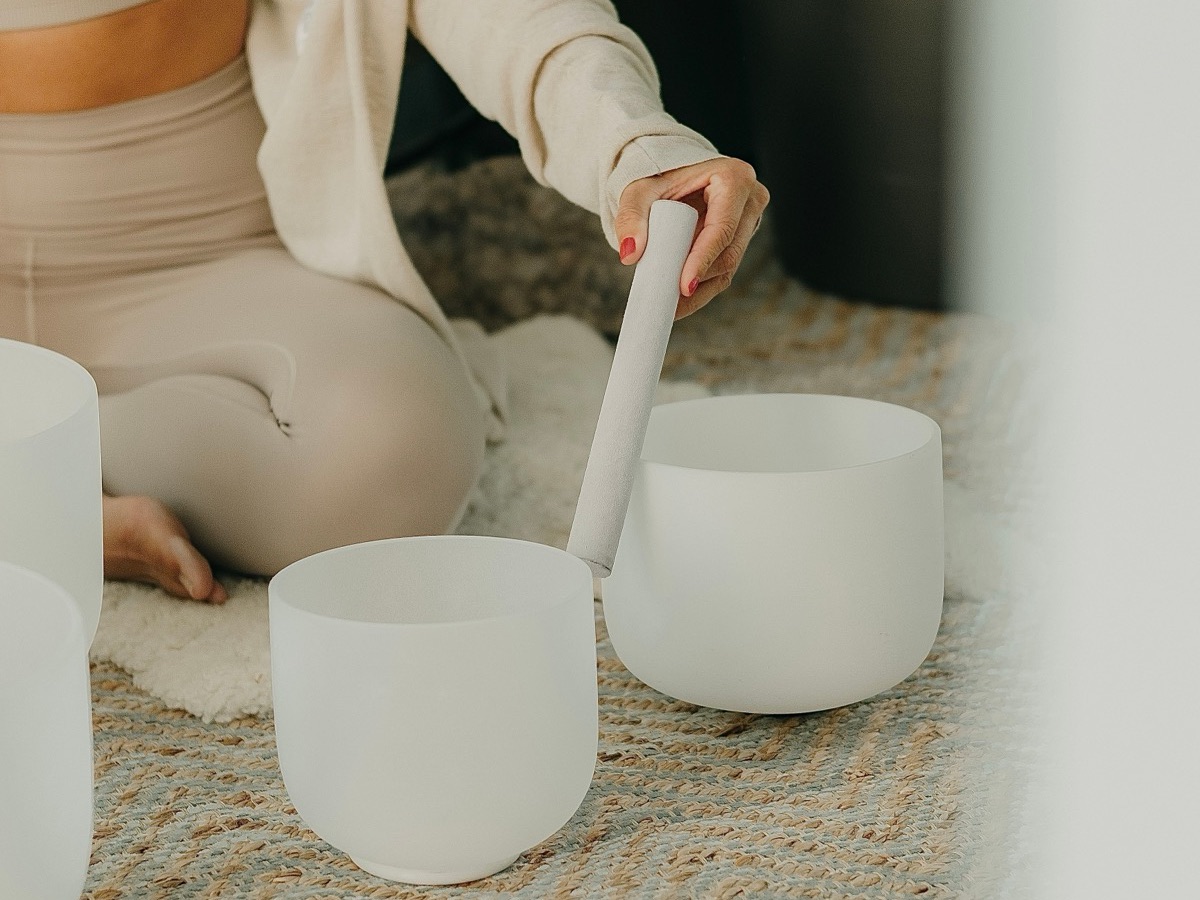 Sound Healing mit weißen Klangschalen auf einem Teppich