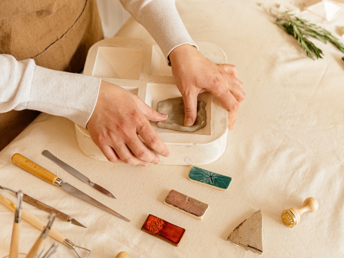 Kreativworkshop: Hände formen Ton an einem Tisch mit Werkzeug